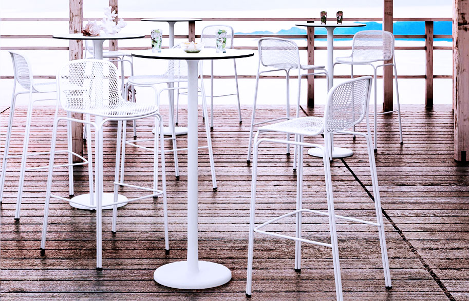 Chaises hautes et tables hautes blanches sur terrasse extérieure